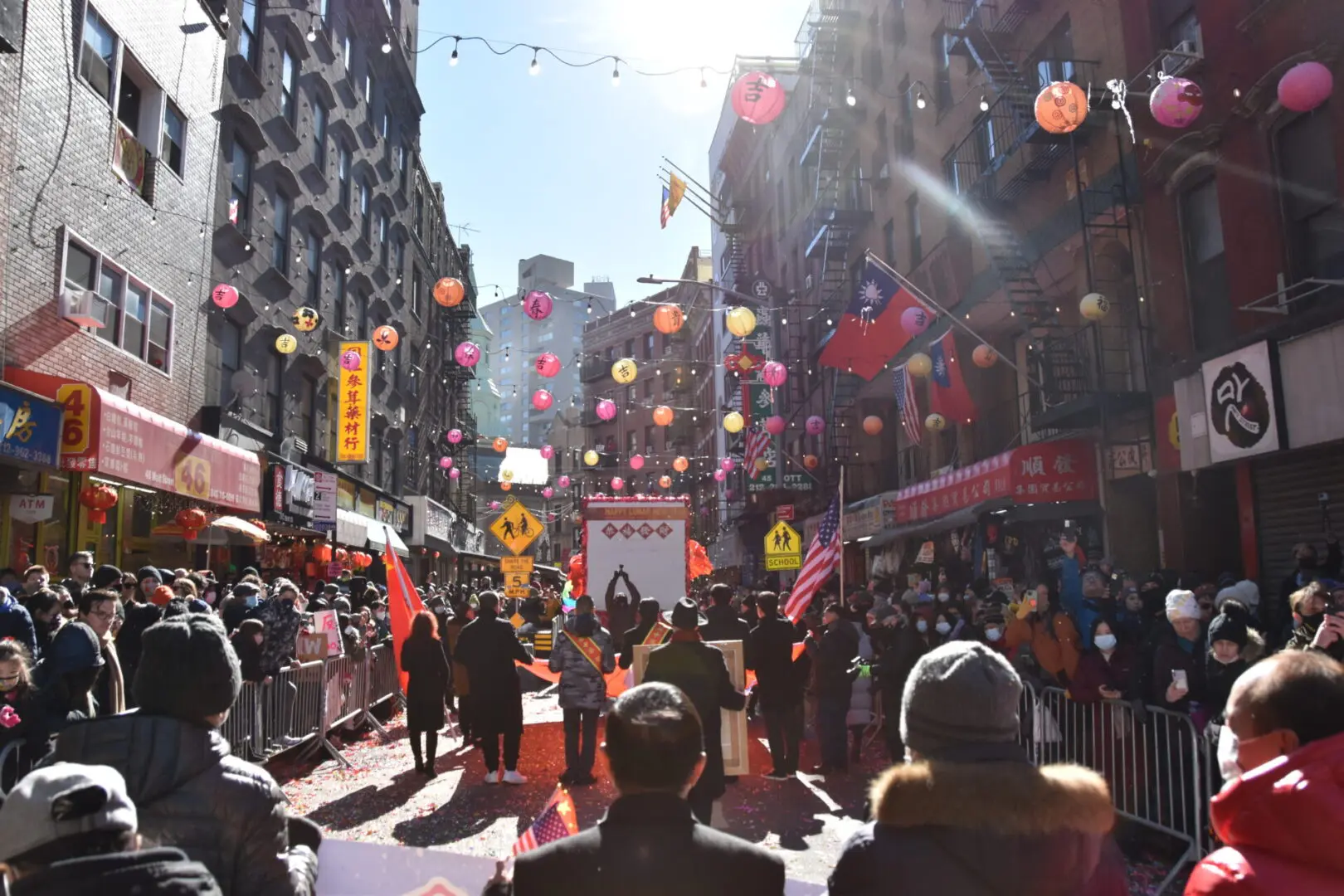 Crowd enjoying a sunny street festival with colorful lanterns.