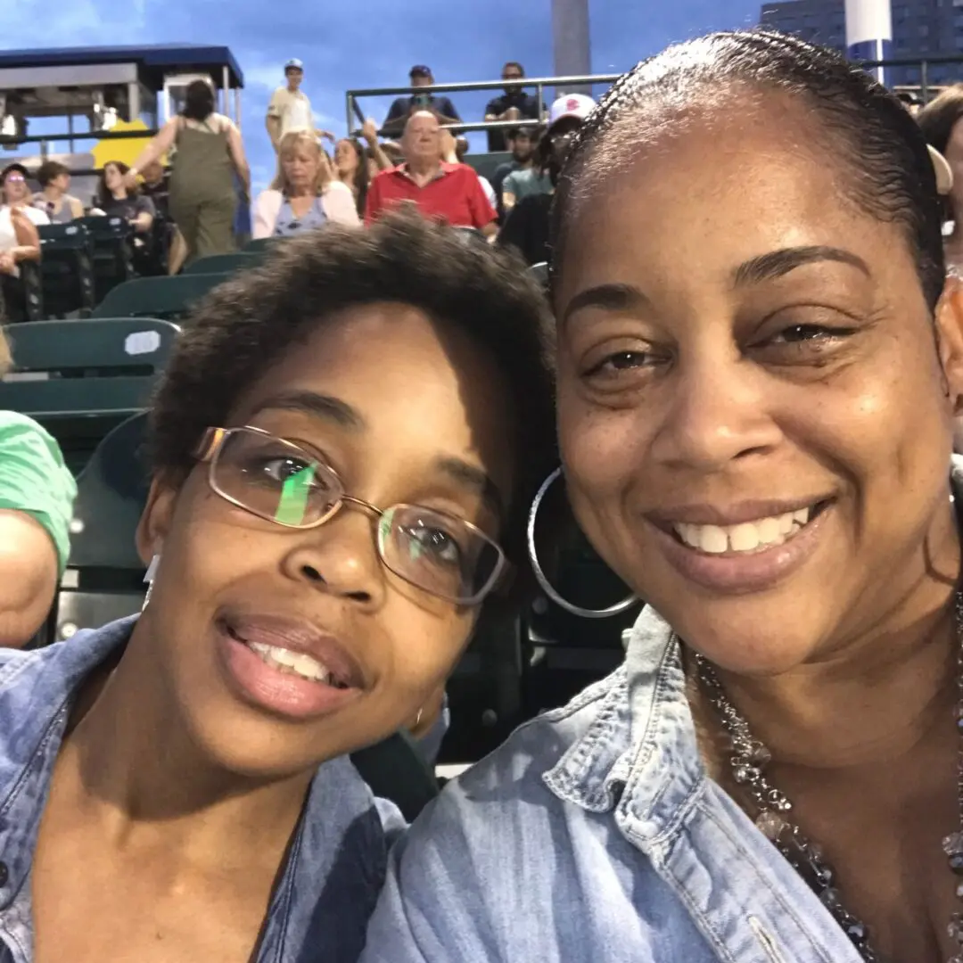 Two women smiling closely together at an outdoor event.