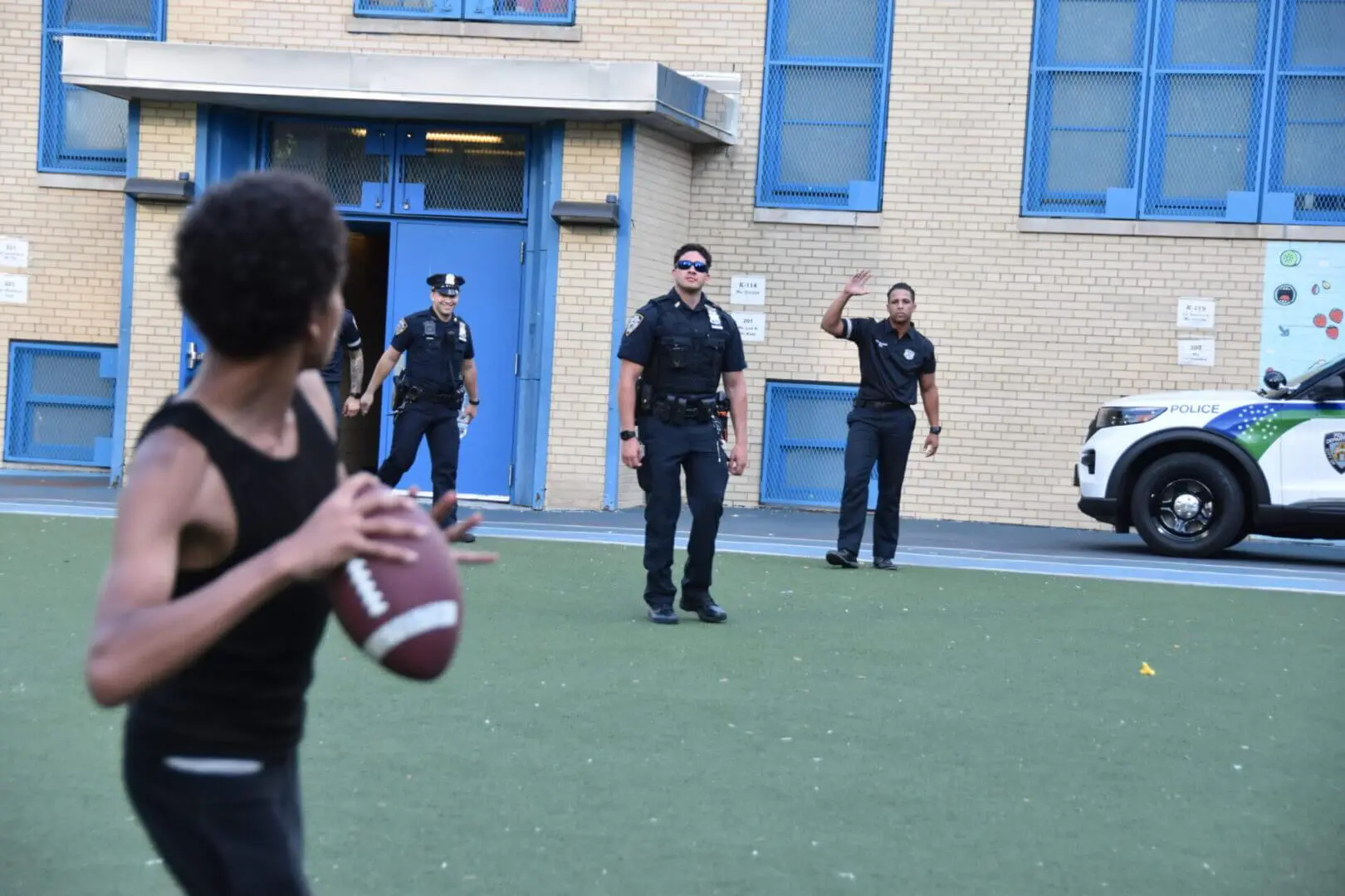 A person throwing a football to police officers standing on a field.