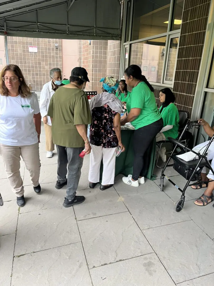 People gathering outdoors, some wearing masks and green shirts.