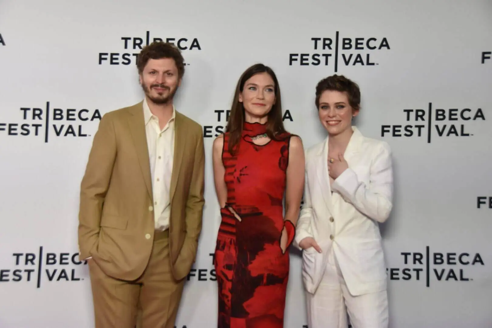 Three people posing at Tribeca Film Festival, dressed in formal attire.