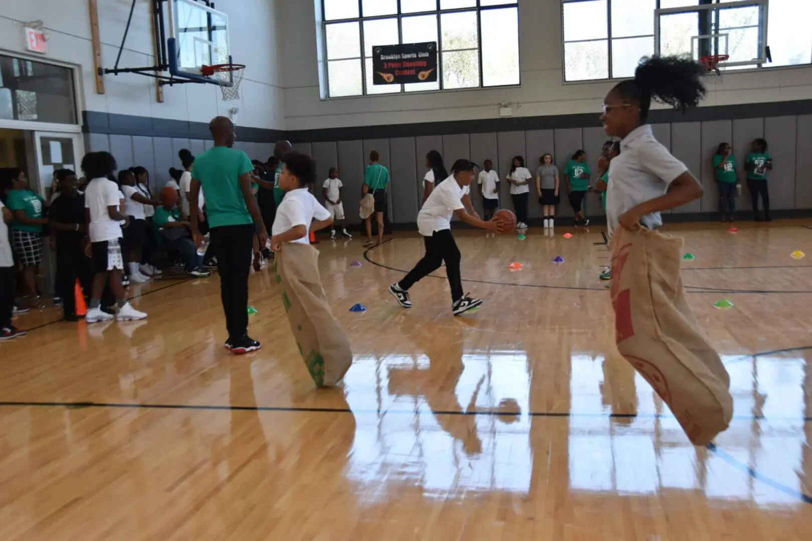 Children participating in a sack race in a gymnasium.