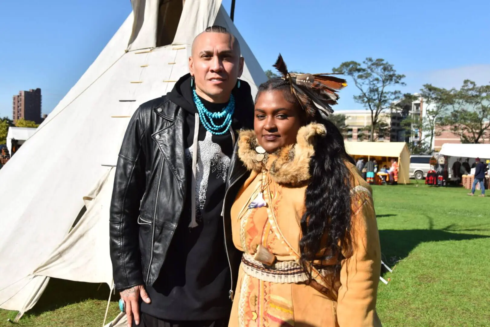Two people posing outdoors on a sunny day.