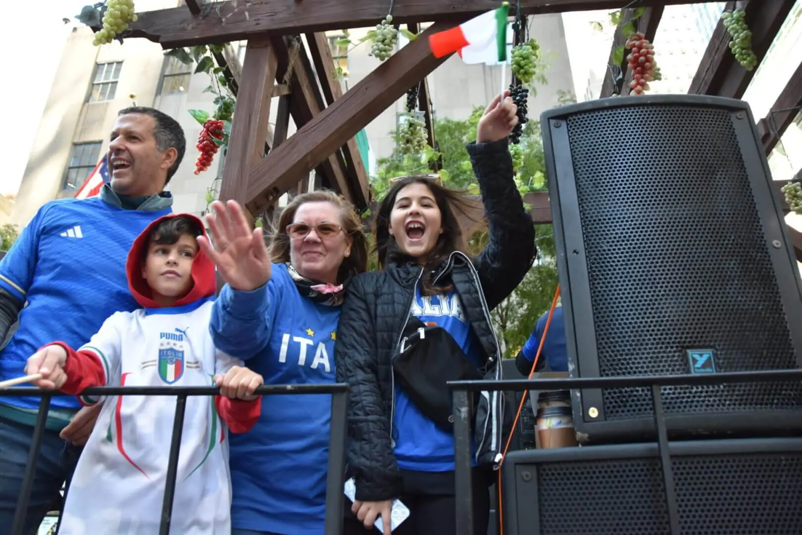 Excited crowd cheering with drinks raised at an outdoor event.