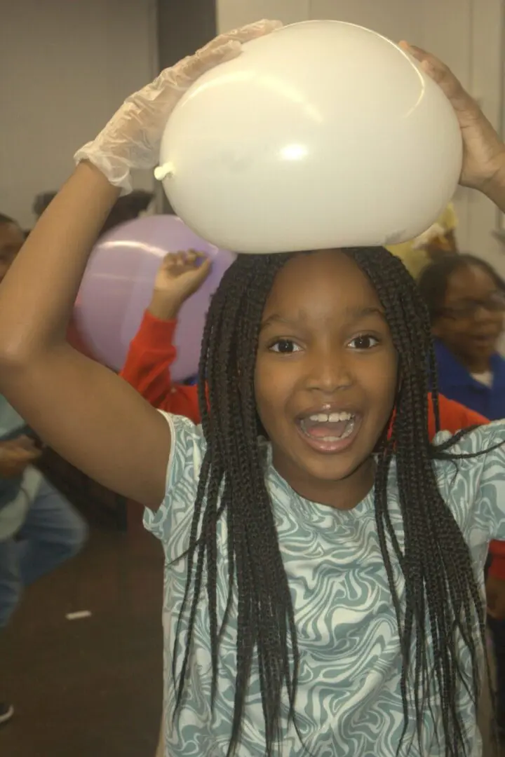 Girl joyfully holding a bowl above her head in a lively setting.