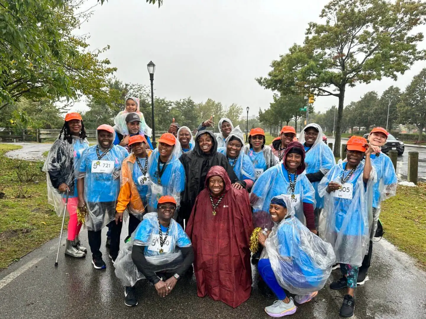 Group of people outdoors wearing rain ponchos and orange caps.