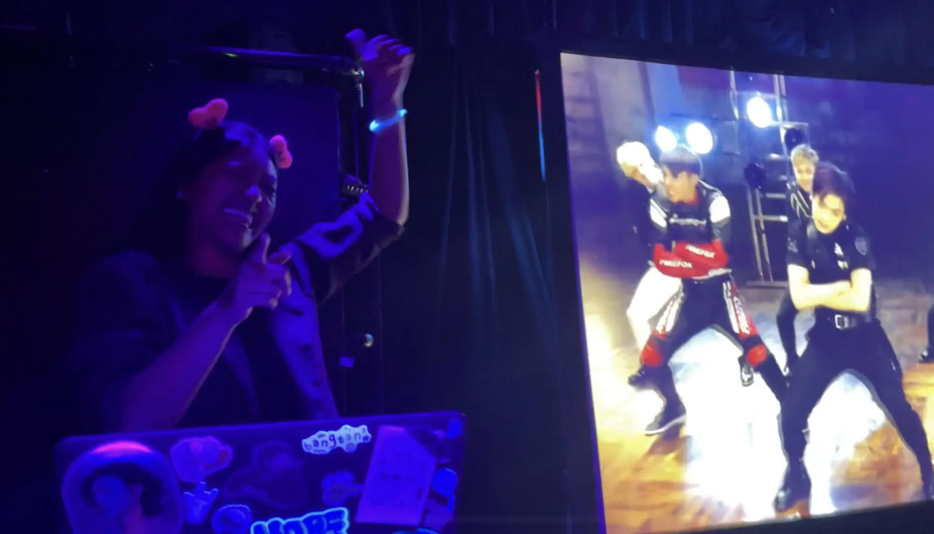 Person interacting with a large screen showing a dancing character.