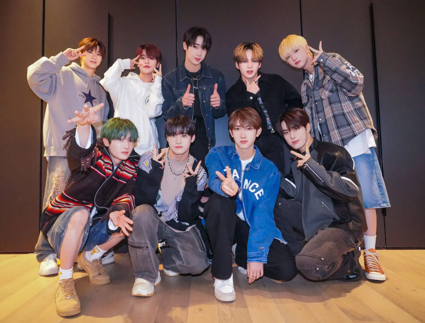 A group of eleven people posing indoors, some making peace signs.