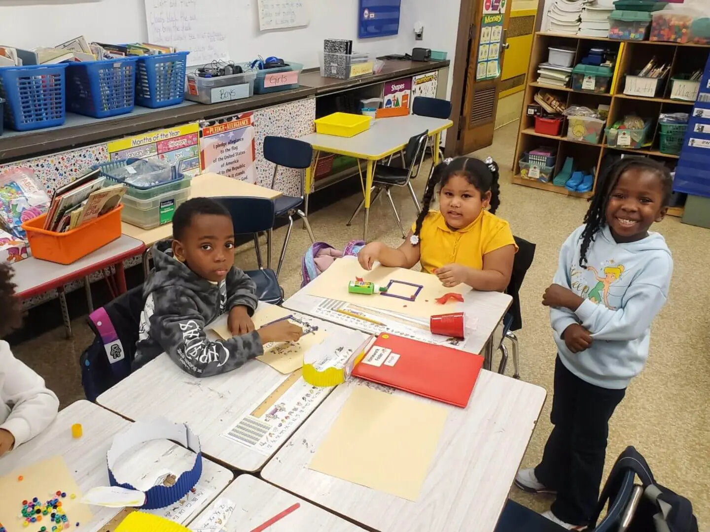 Children happily engaging in classroom activities at a table.