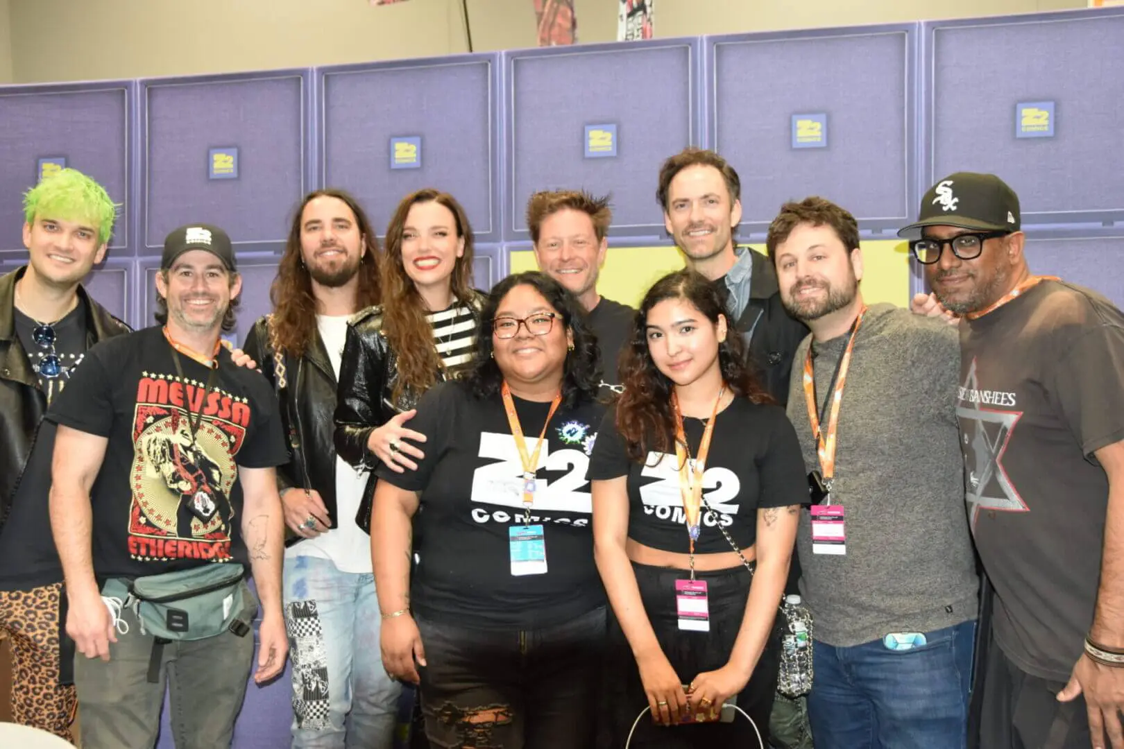 Group of smiling people posing together indoors with event badges.