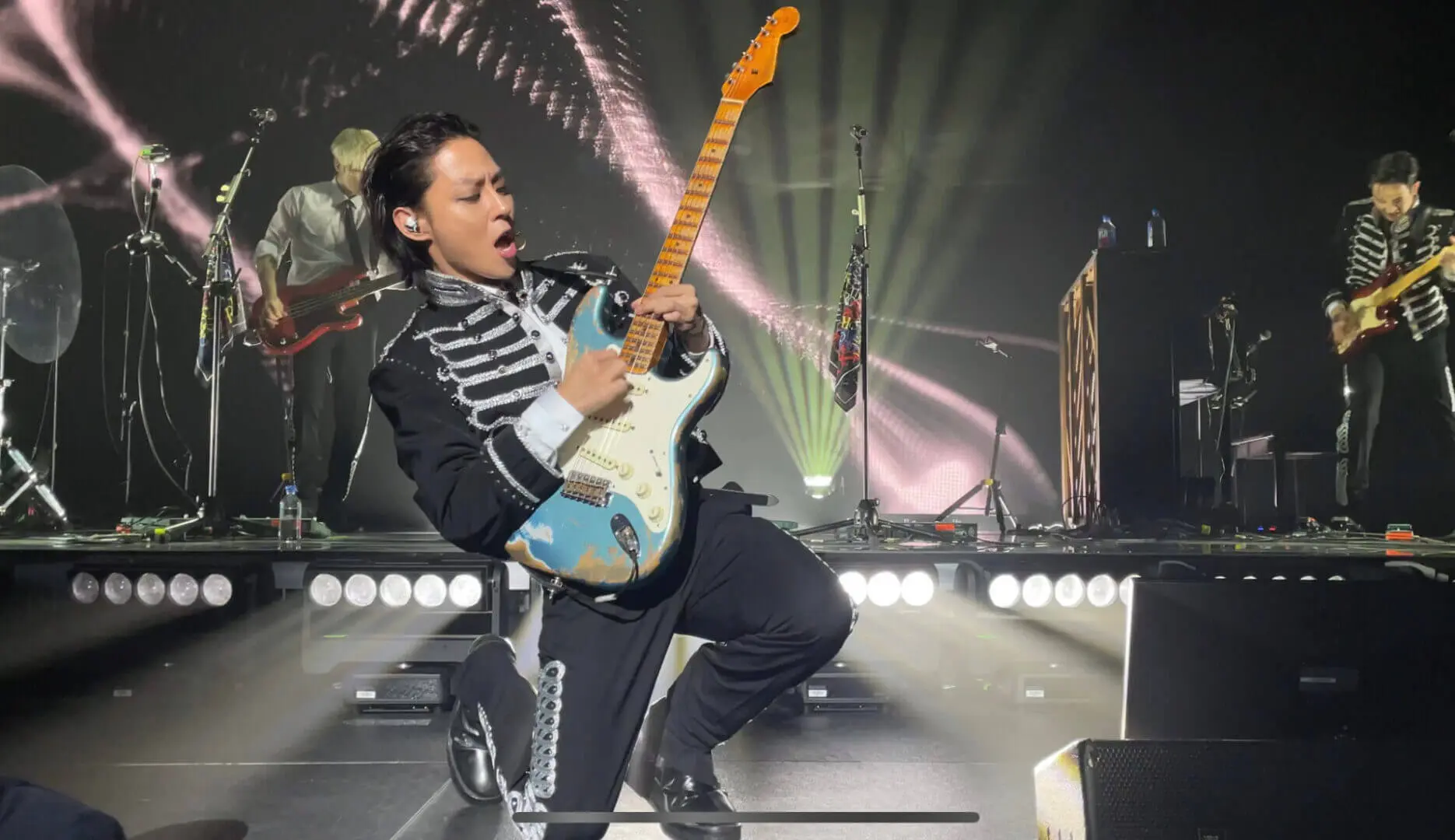 Guitarist passionately playing on stage with dramatic lighting.