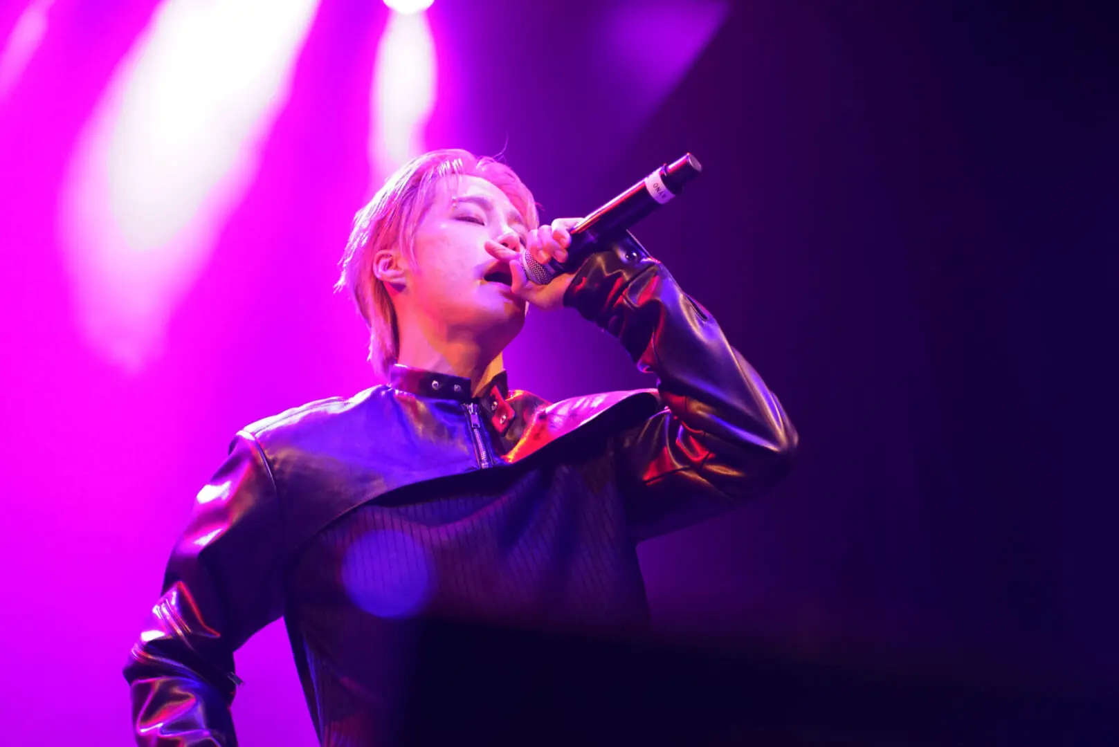 Singer passionately performing on stage under purple lights.