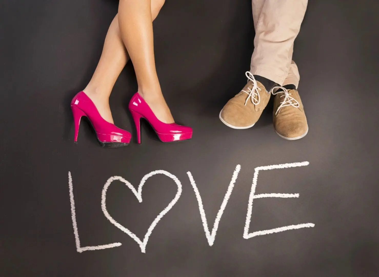 Two pairs of feet with 'LOVE' written on the floor.