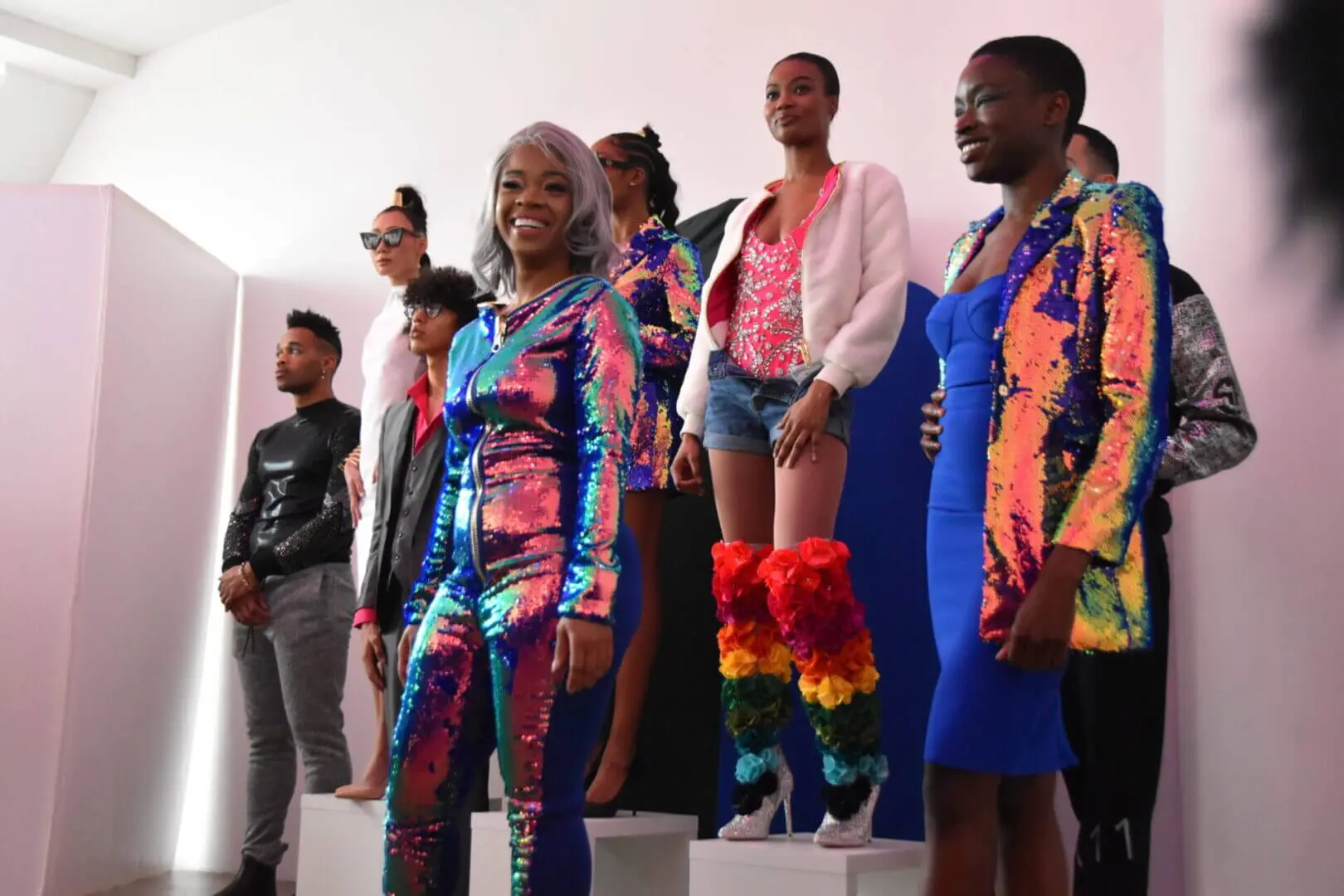 A group of models showcasing vibrant, colorful fashion designs on a runway.