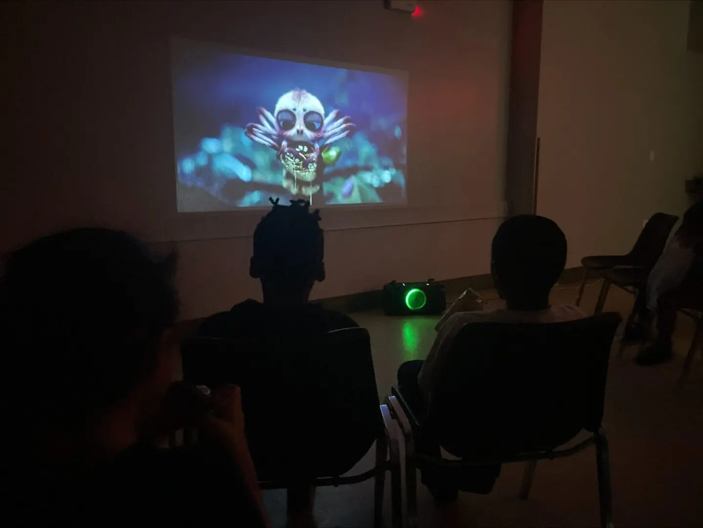 People watching a spooky skeleton animation in a dark room.