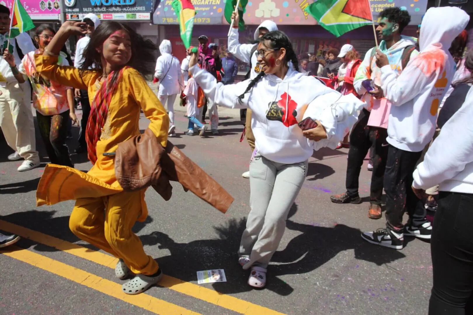 People joyfully dancing on the street during a lively outdoor event.
