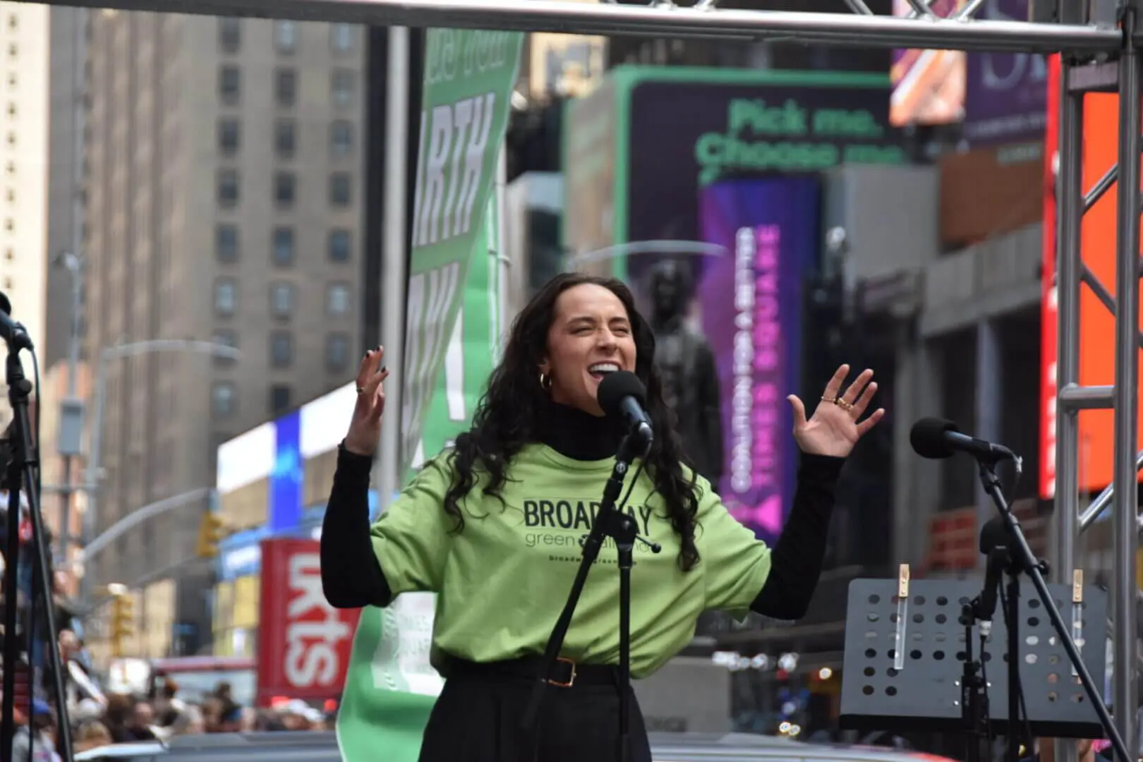 A woman passionately speaking at an outdoor event in a city.