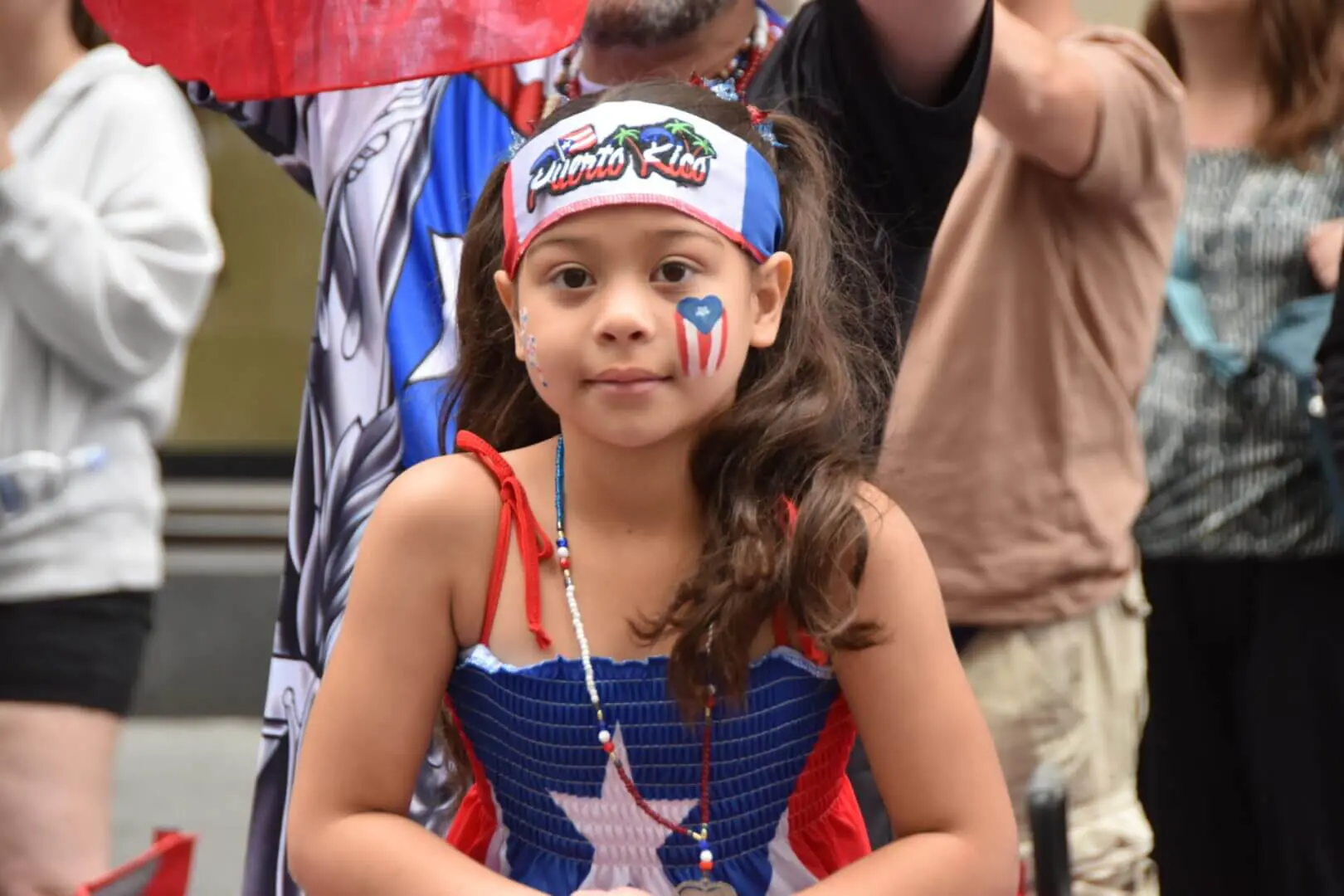 Young girl dressed patriotically with face paint and headband.