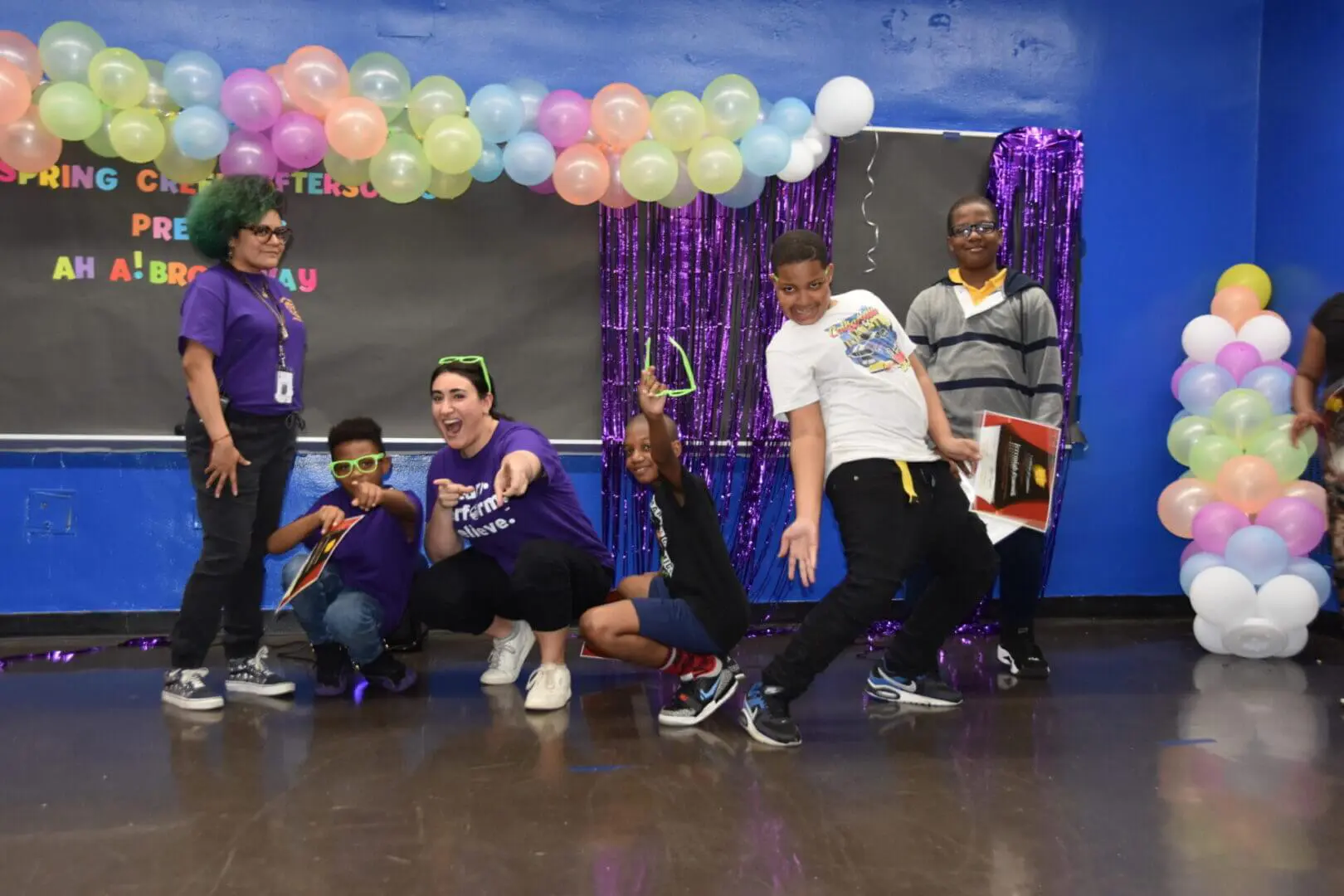 Group of people joyfully dancing and posing indoors with colorful balloons.
