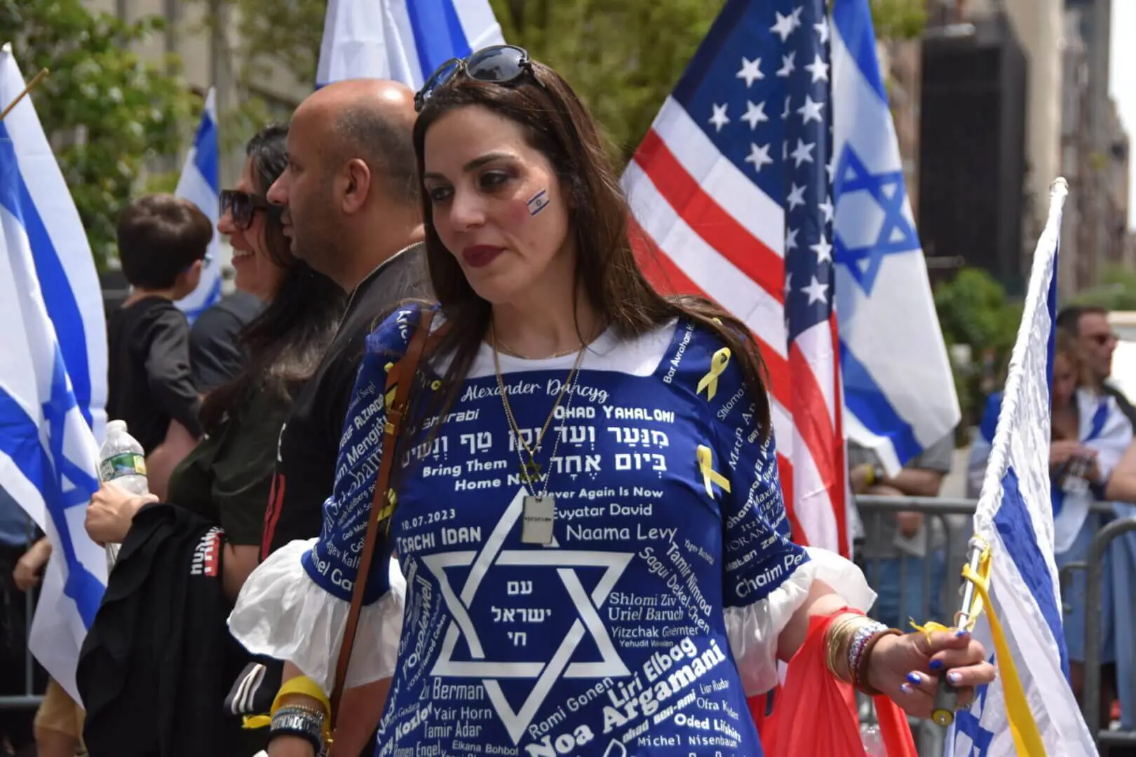 Woman wearing a Star of David shirt with Israeli and American flags behind her.