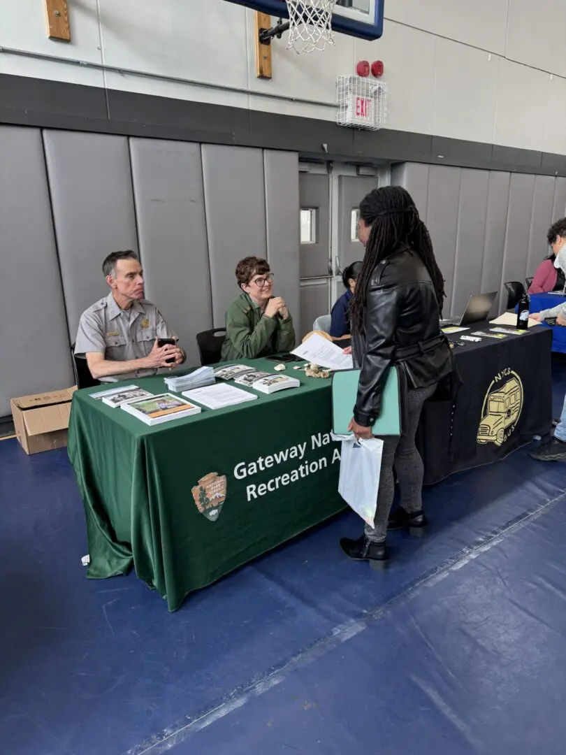 Two representatives at a college booth talking to a visitor.