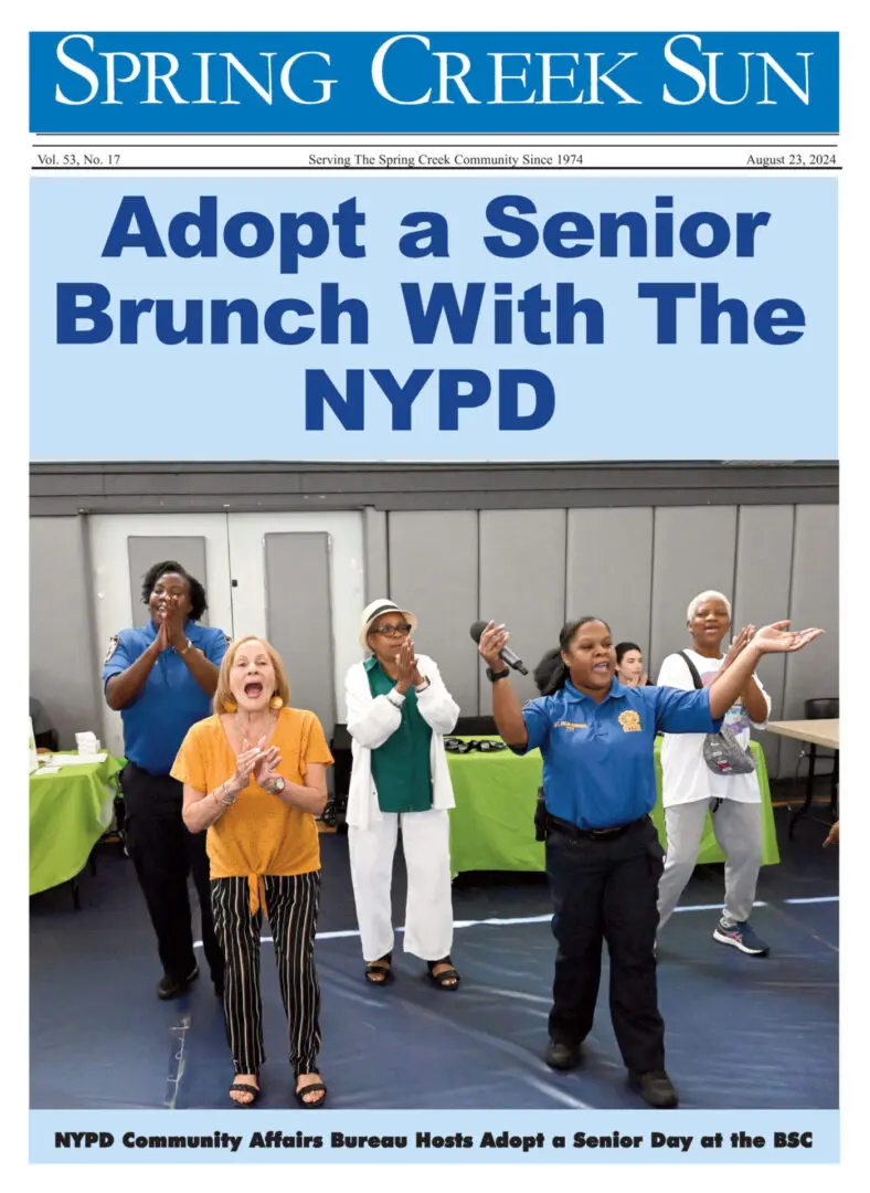 NYPD officers and seniors joyfully pose outdoors for an Adopt a Senior Brunch event.