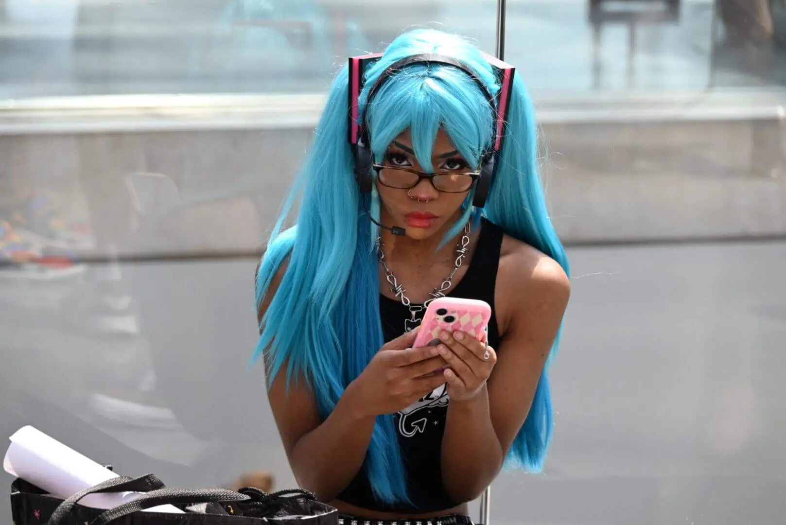 Person with long blue hair and glasses using a phone.