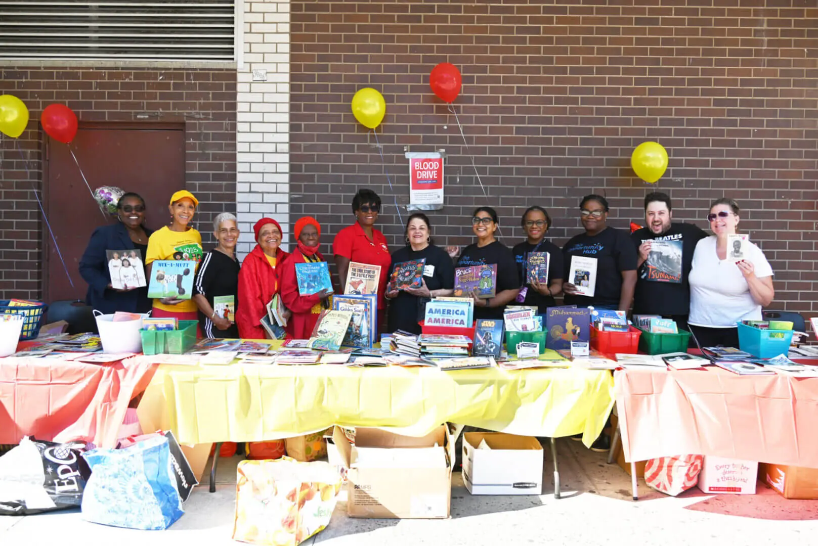 Group of people standing behind a table with books and balloons.