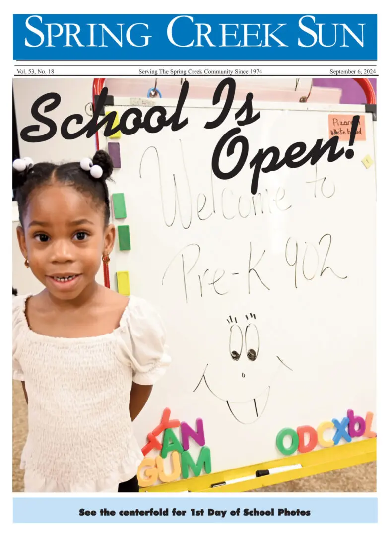 Smiling young girl announces school is open with colorful letters.