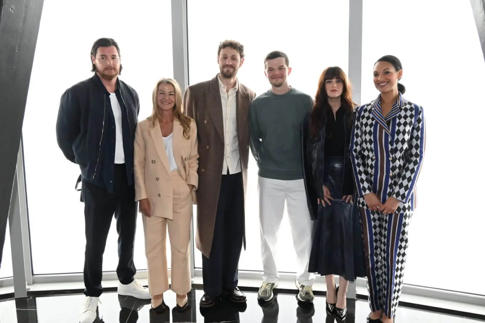 A diverse group of six people standing together indoors, smiling.