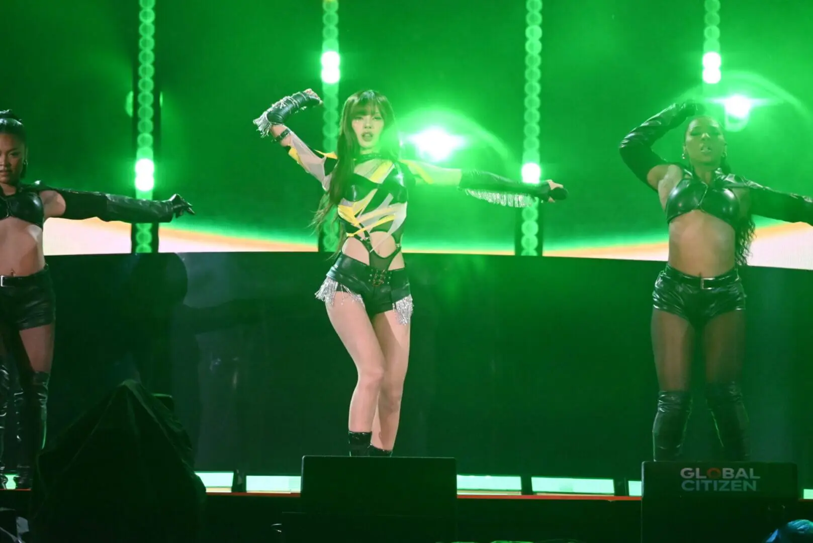Female performer in black outfit dancing under green stage lights.