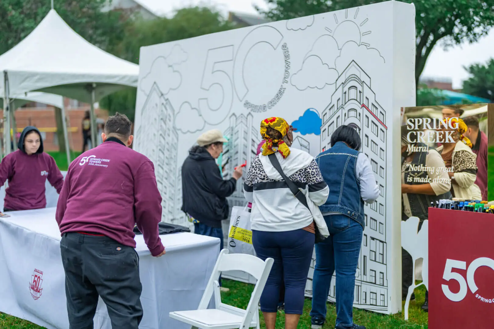 People painting a large collaborative mural outdoors.