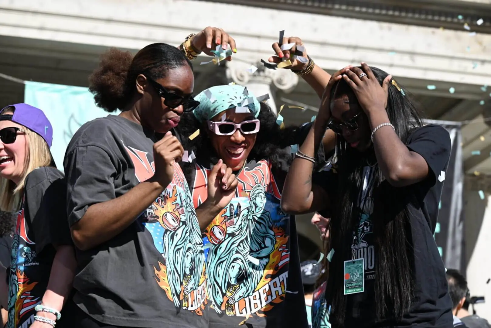 Three friends having fun with drinks at a lively outdoor event.