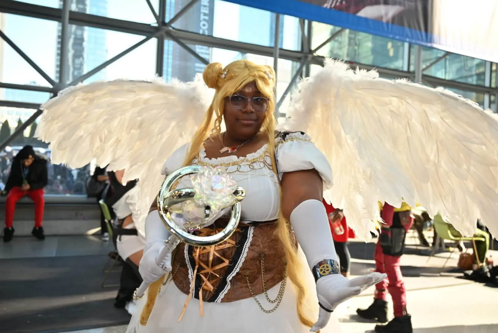 Cosplayer dressed as a winged angel with golden hair and armor.