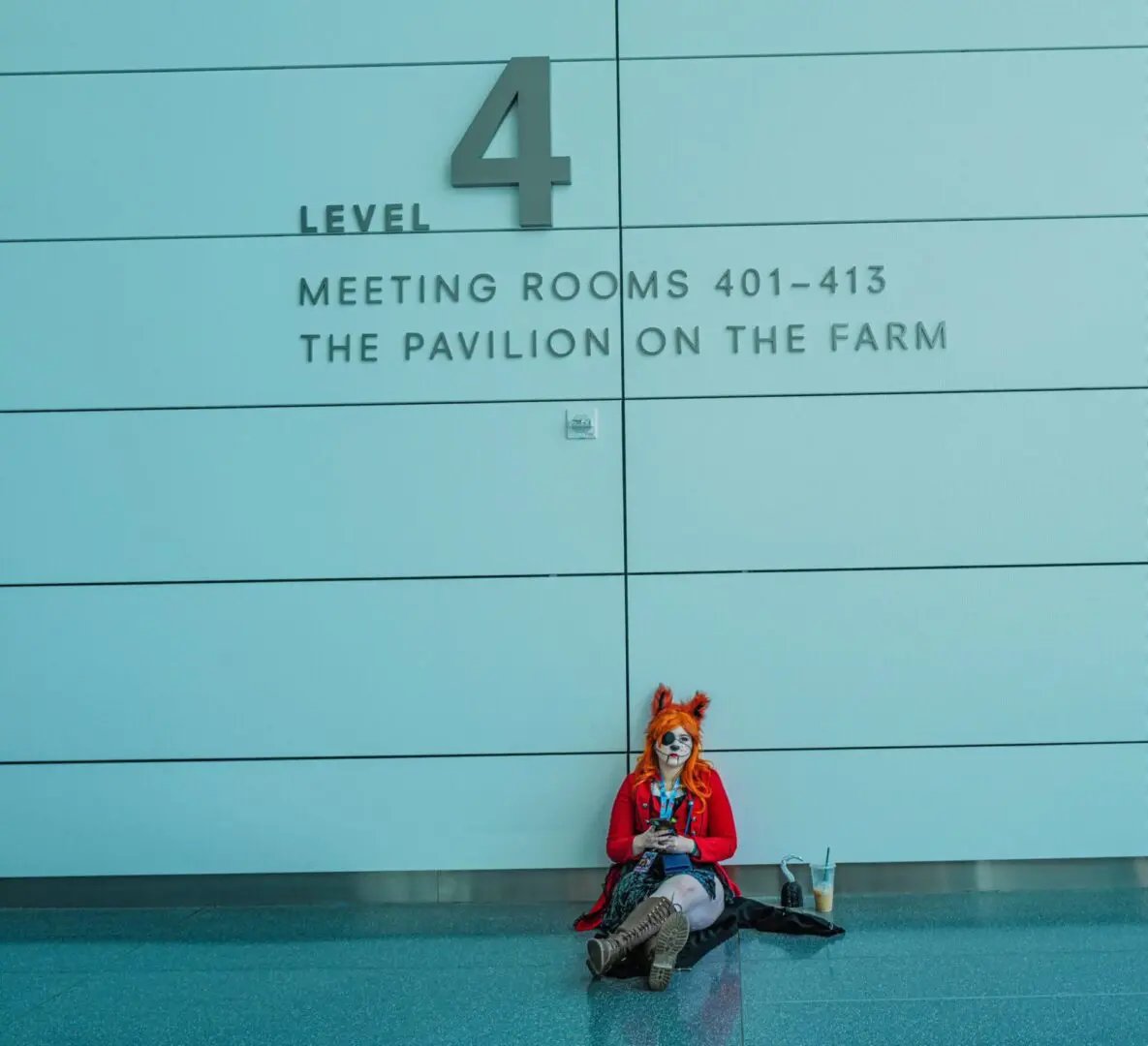 Person sitting against a wall marked Level 4 with meeting room information.