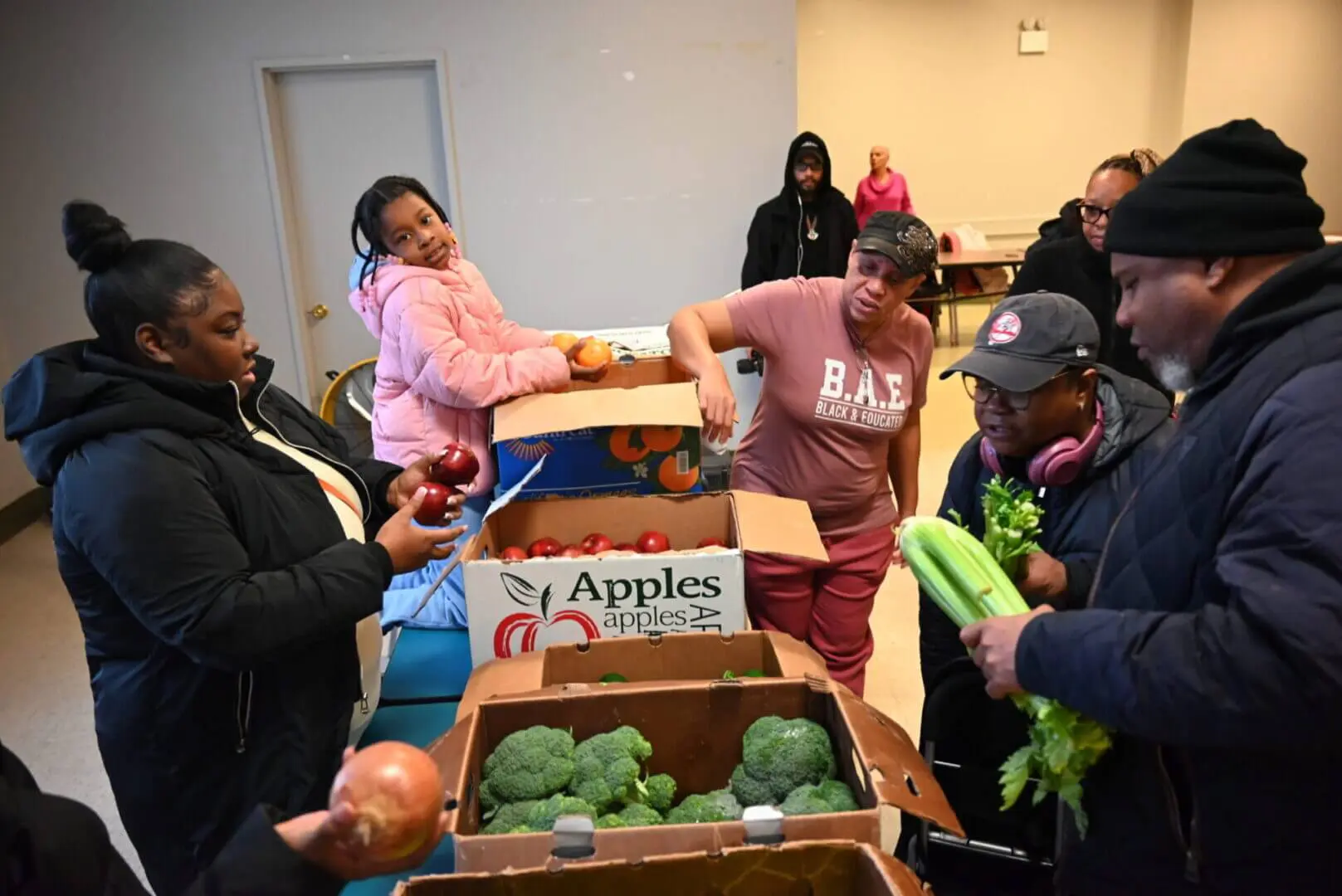 Children distributing vegetables at a community event indoors.