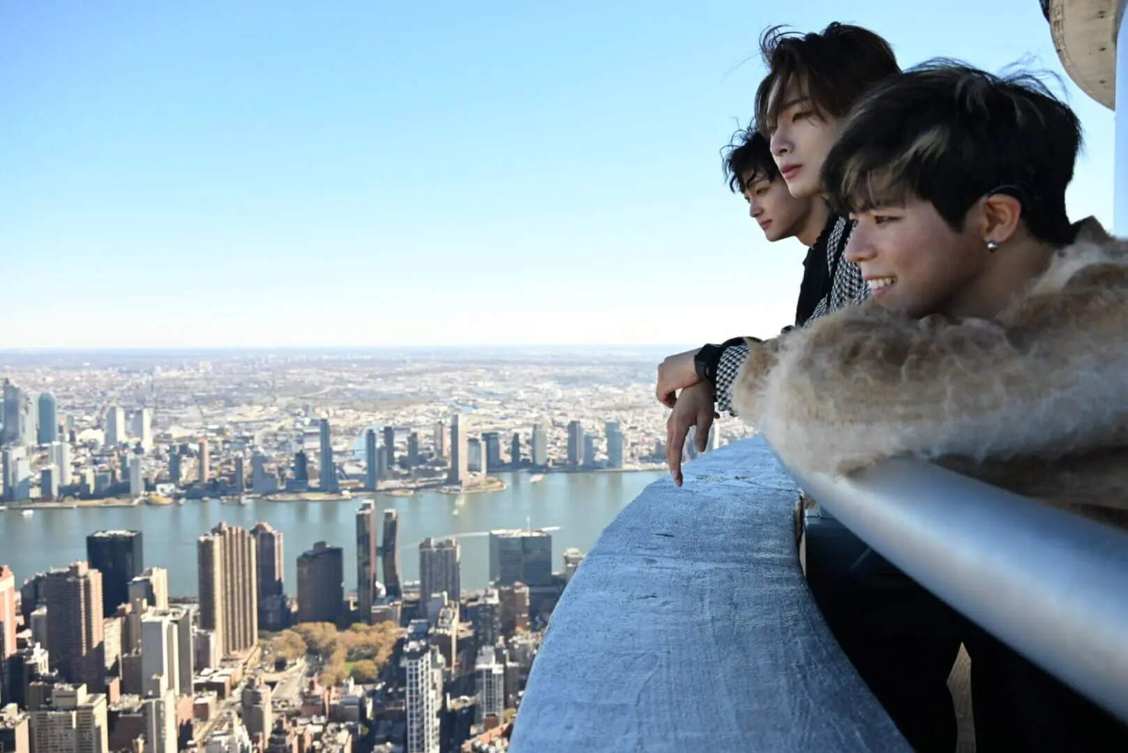 Three people enjoying a cityscape view from a high vantage point.
