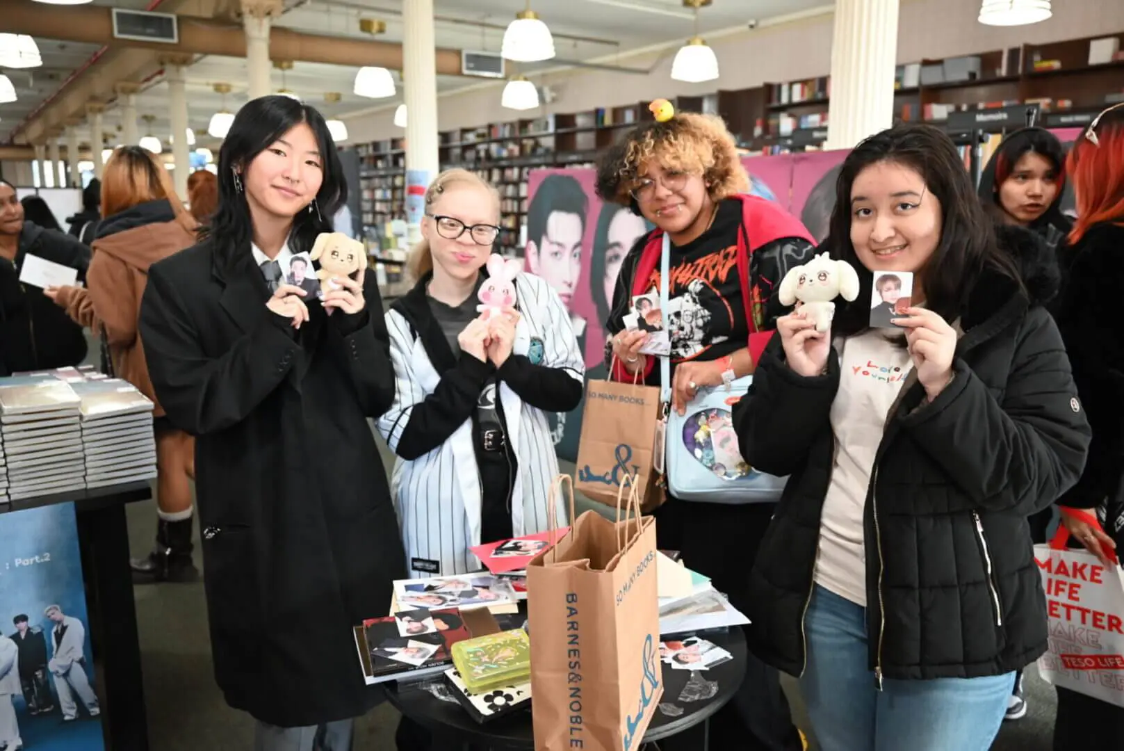 Four women happily showing decorated mugs in a cozy cafe setting.