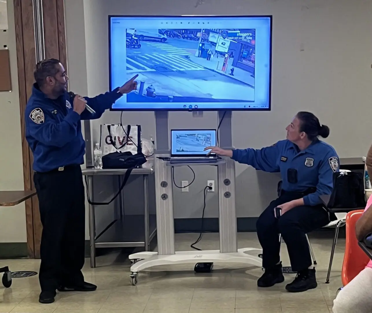 Two security officers reviewing footage on a monitor in a control room.