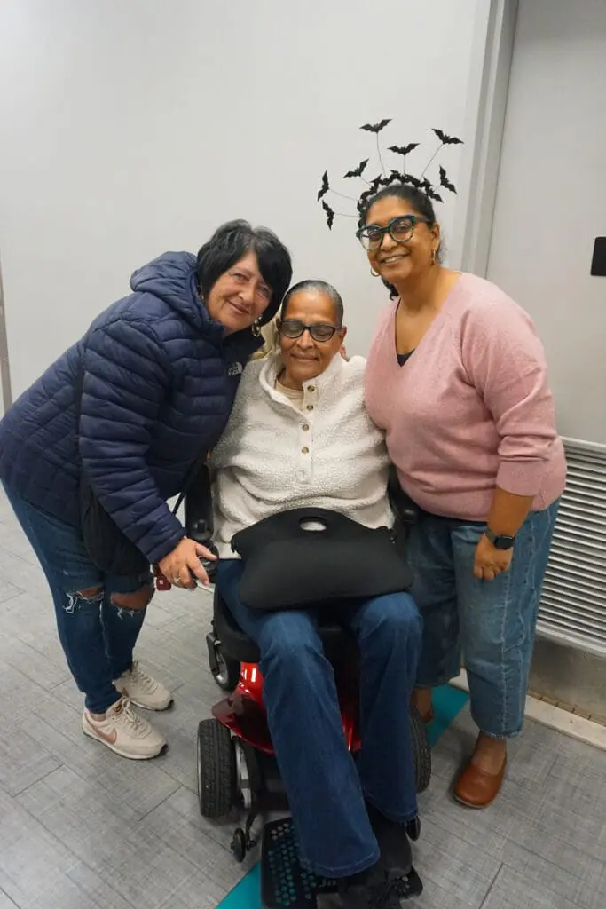 Three people smiling, one in a wheelchair.
