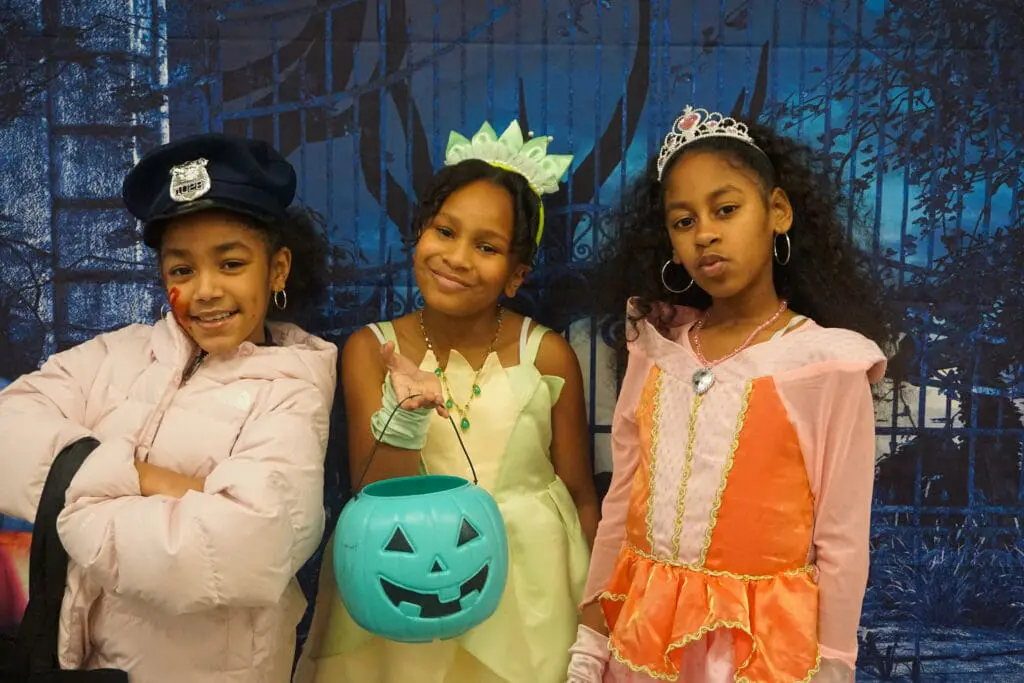 Three children in Halloween costumes smiling.