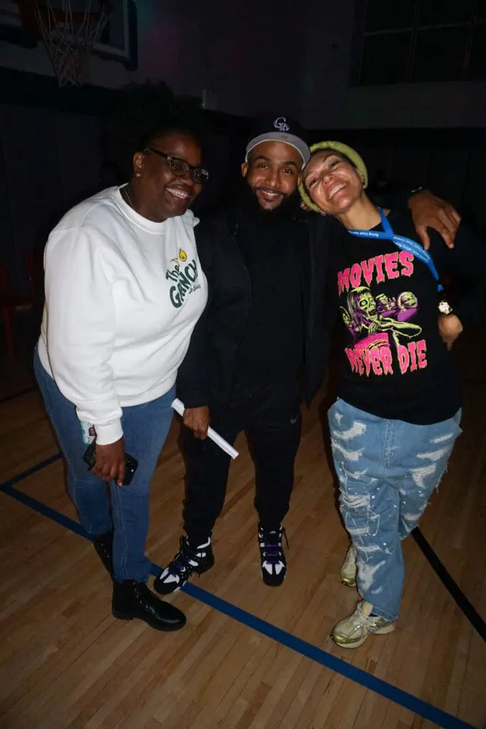 Three people smiling in a gymnasium.