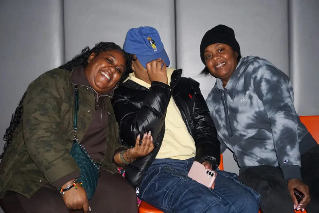 Three people smiling and sitting together.